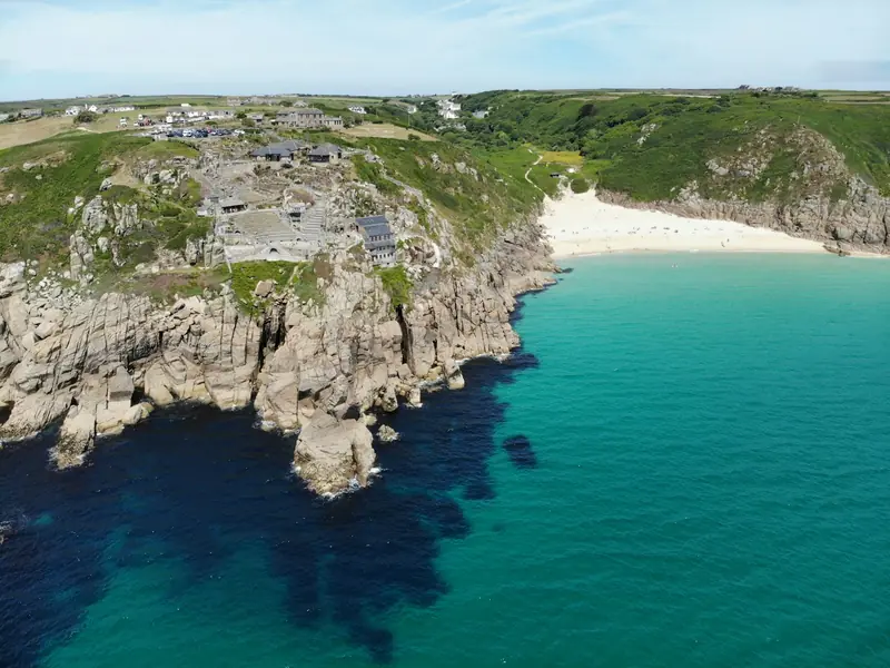 Côte sauvage bretonne avec falaises rocheuses et phare au loin sous ciel dramatique