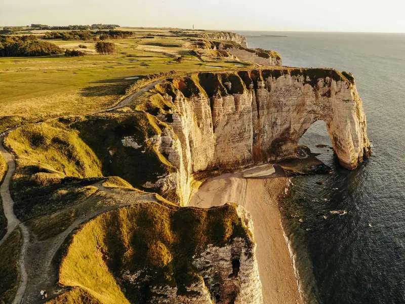 Falaises blanches d'Étretat en Normandie avec arche naturelle sous lumière dramatique