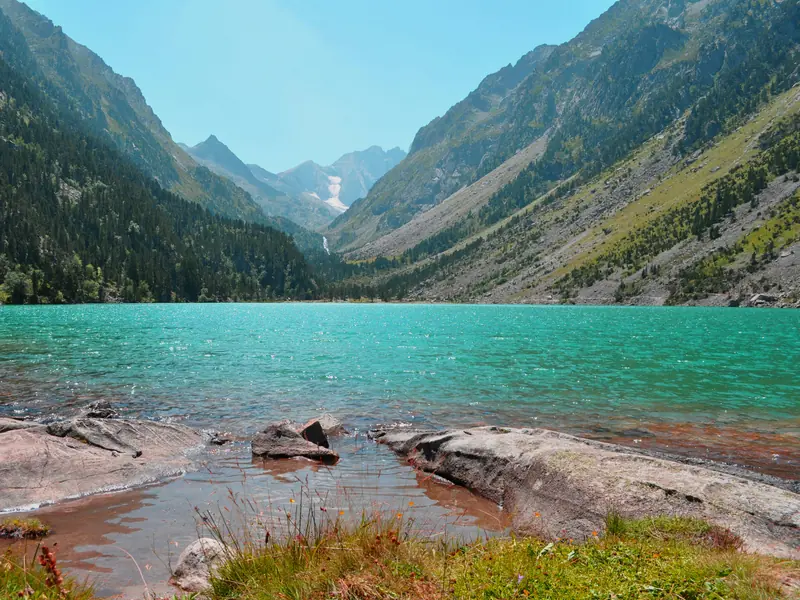 Lac de montagne dans les Pyrénées avec sommets rocheux et van aménagé au bord de l'eau