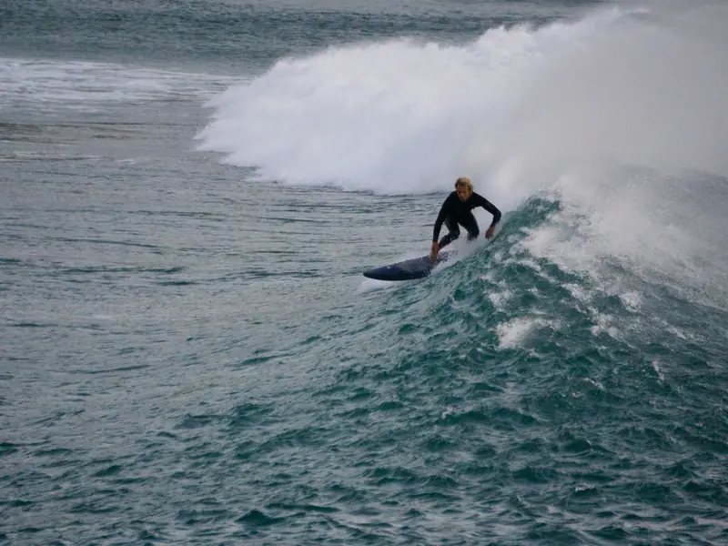 Surfeur sur les vagues de la côte basque à Biarritz avec van aménagé garé sur la plage